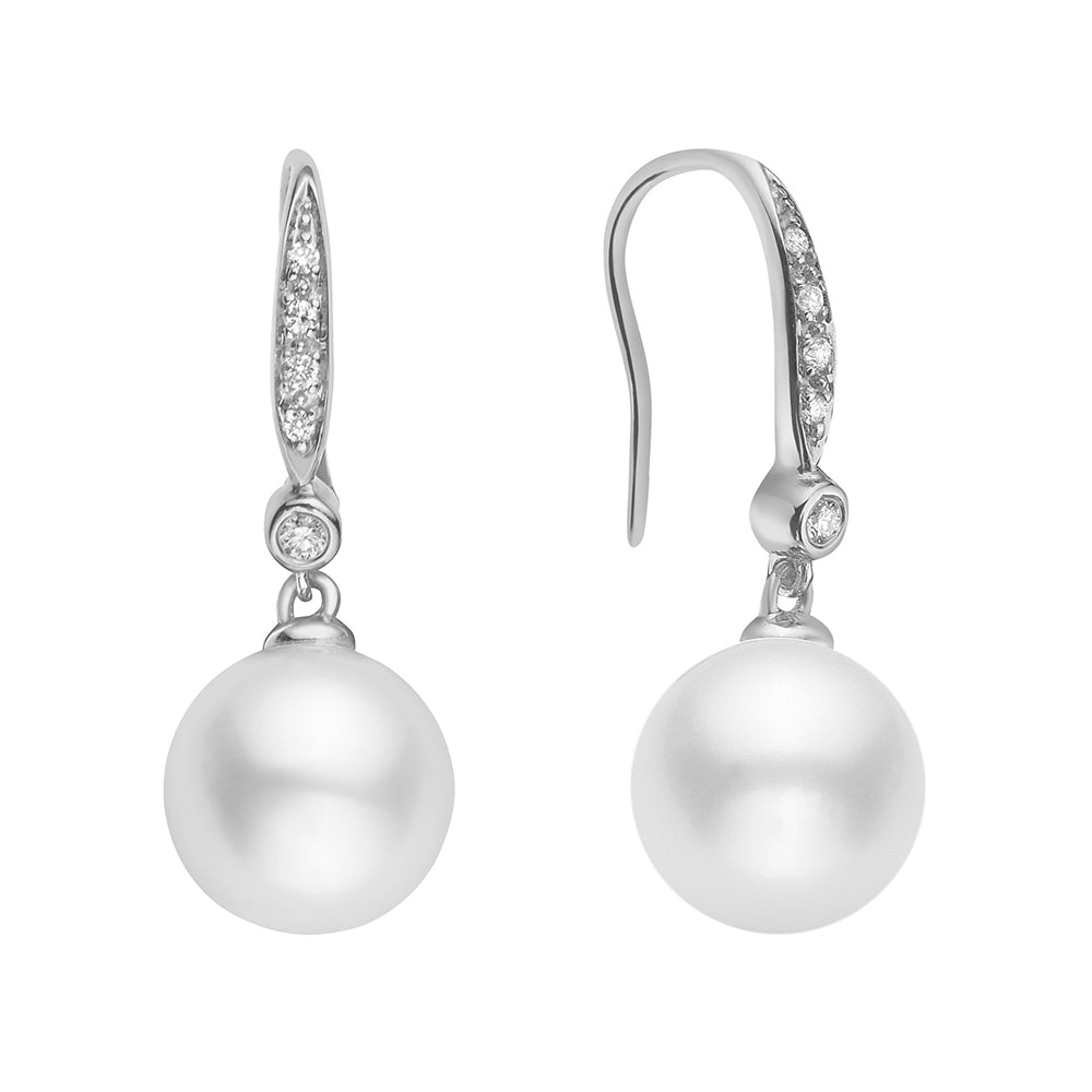 A pair of 14K white gold dangle earrings featuring round brilliant cut diamonds leading to a bezel-set diamond, with a luminous freshwater pearl at the base.