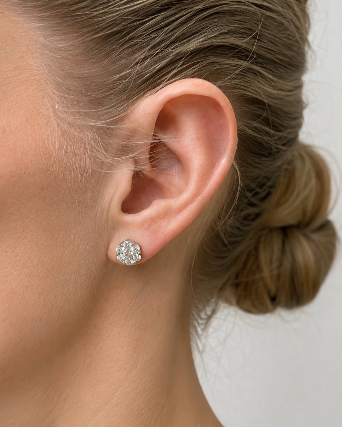 A model wearing white gold flower cluster stud earrings. 