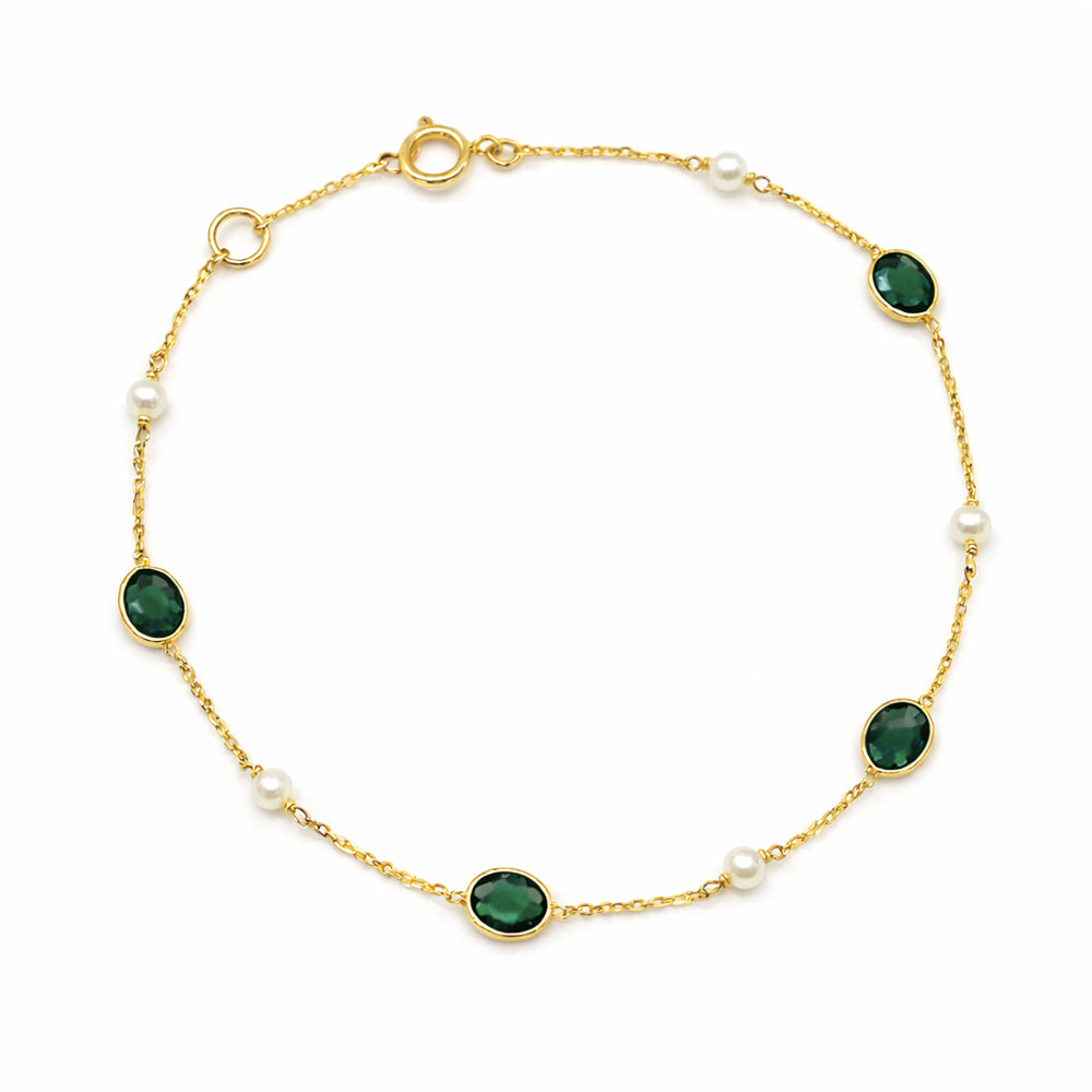 Gold bracelet with green gemstones and pearls on a white background