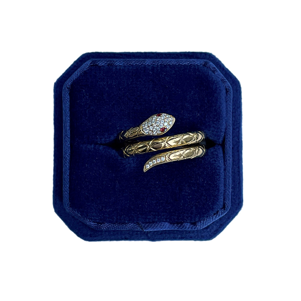 Gold snake-shaped ring in a blue velvet box on a white background