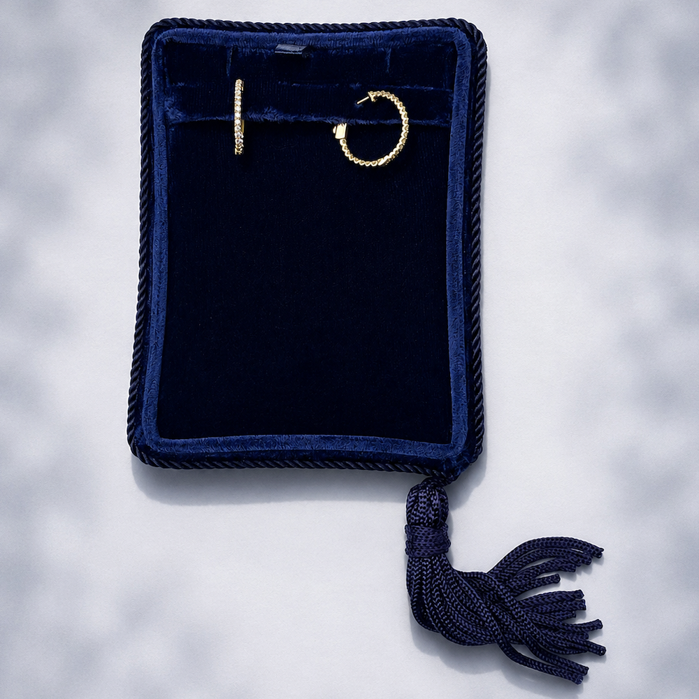 Razor thin gold diamond hoop earrings in a blue velvet jewelry box on a white background.