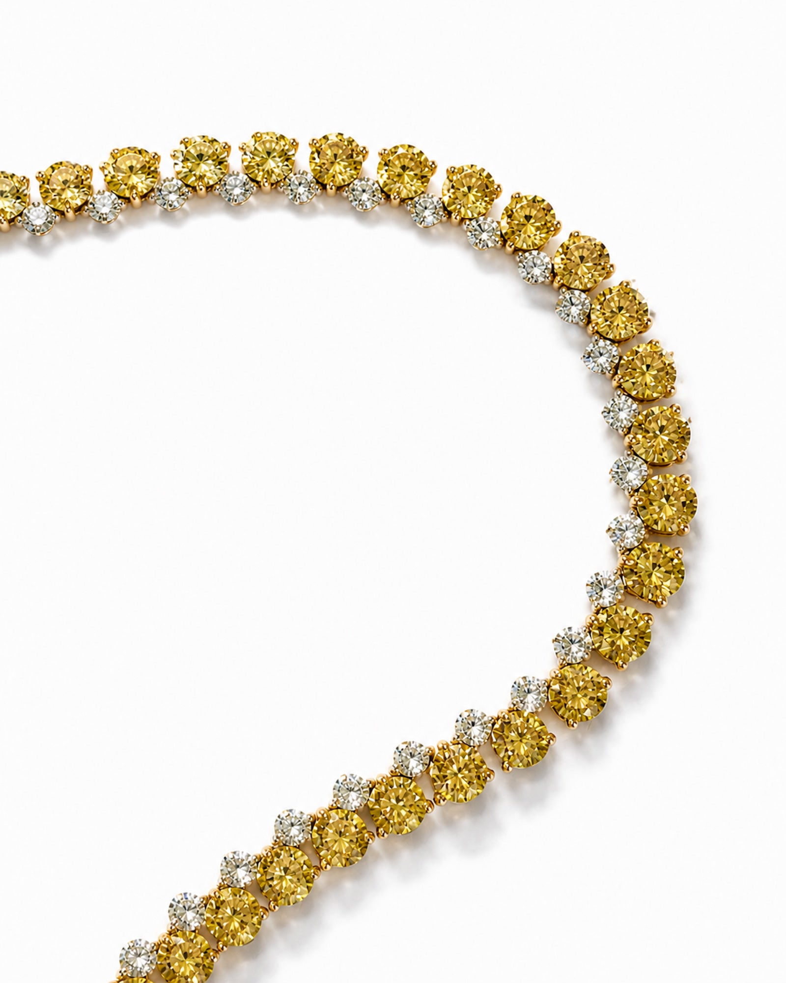 Close-up of an alternating white and yellow diamond tennis necklace featuring natural round brilliant diamonds in 18K white and yellow gold.