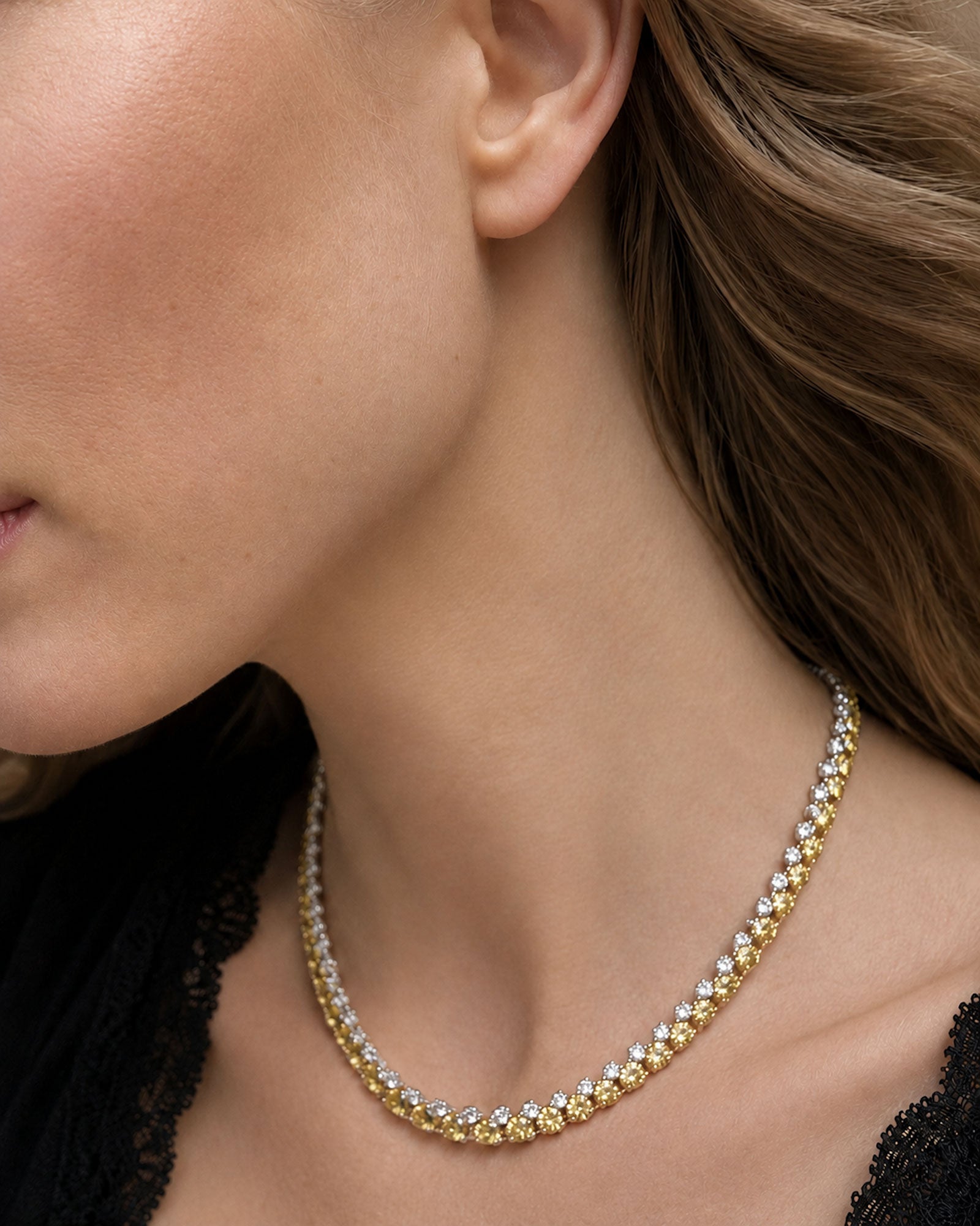 Side view of an alternating white and yellow diamond tennis necklace featuring natural round brilliant white and yellow diamonds in 18K white and yellow gold.