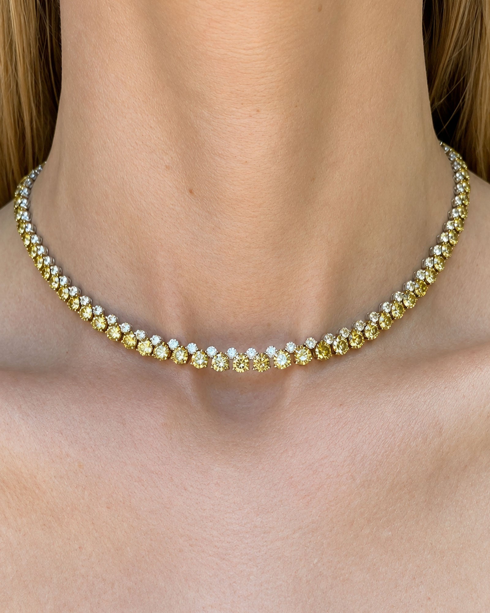 Alternating white and yellow diamond tennis necklace with natural round brilliant diamonds set in 18K white and yellow gold, worn on the neckline.