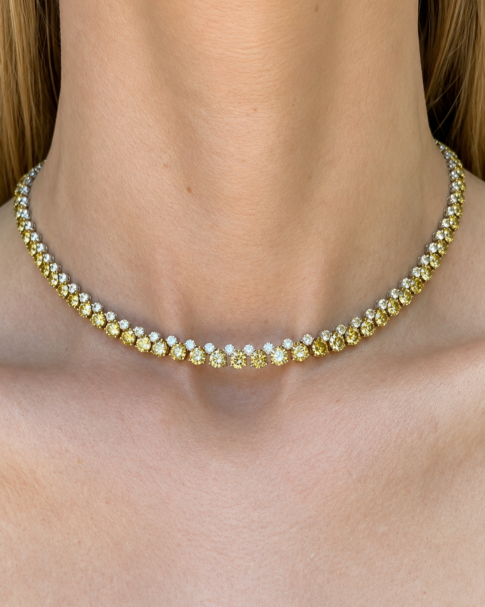 Alternating white and yellow diamond tennis necklace with natural round brilliant diamonds set in 18K white and yellow gold, worn on the neckline.