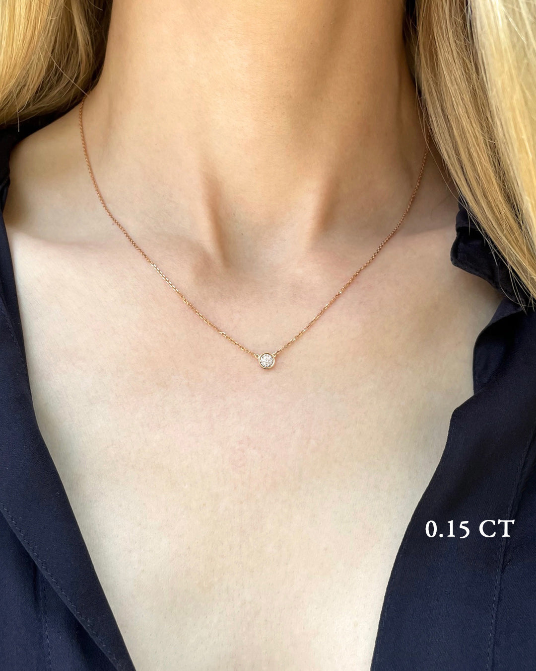 A delicate rose gold necklace with a 0.15 carat diamond, bezel set, shown on a model's neck. 