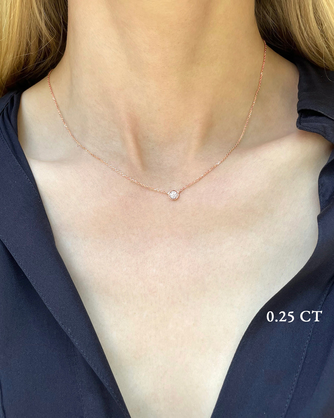 A delicate rose gold necklace with a 0.25 carat diamond, bezel set, shown on a model's neck. 