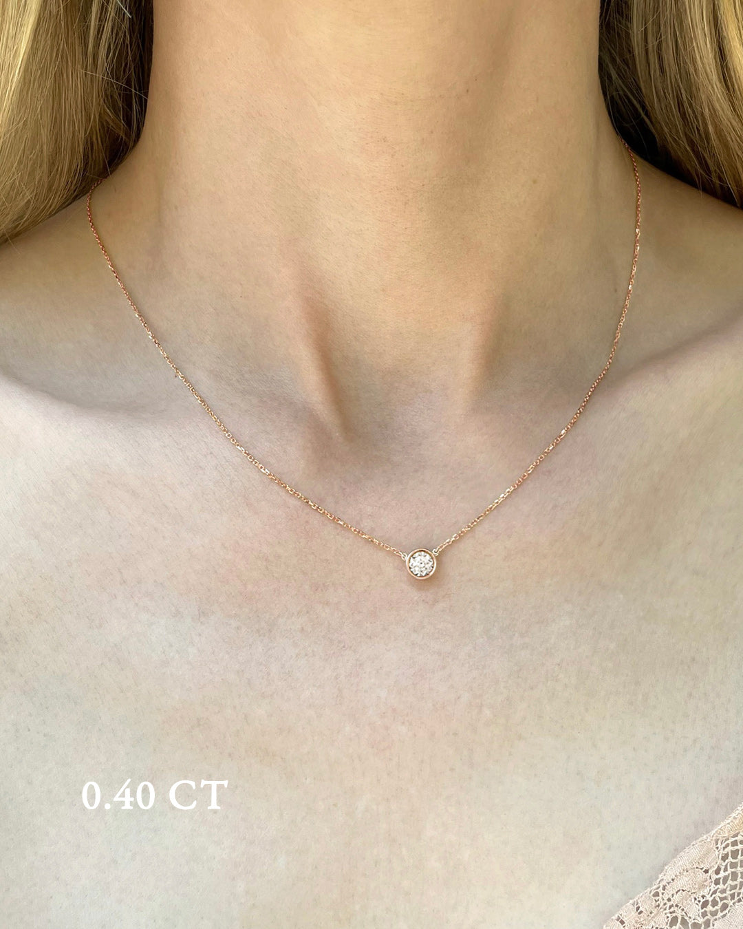 A delicate rose gold necklace with a 0.40 carat diamond, bezel set, shown on a model's neck. 