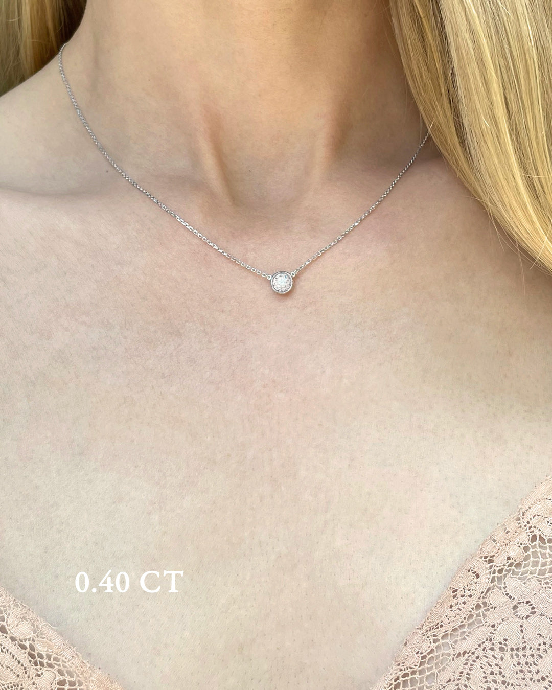 A delicate white gold necklace with a 0.40 carat diamond, bezel set, shown on a model's neck. 
