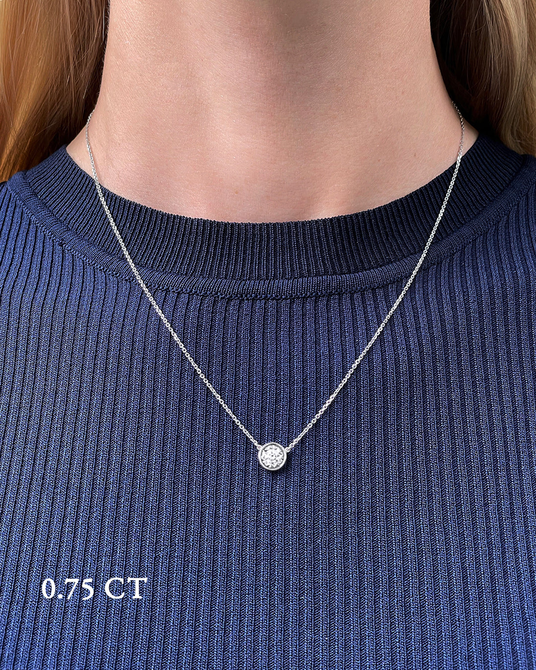 A delicate white gold necklace with a 0.75 carat diamond, bezel set, shown on a model's neck. 