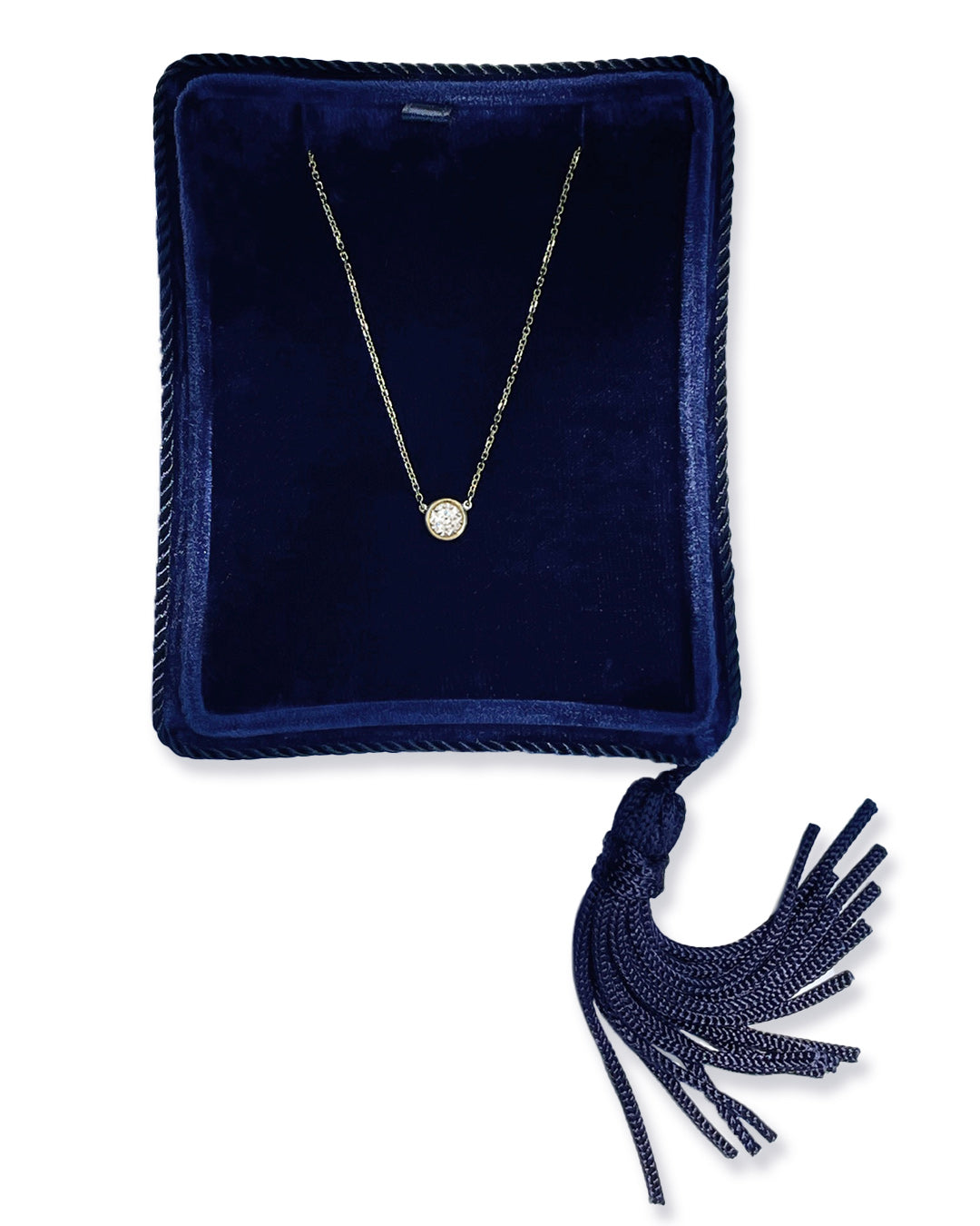 A delicate 14k yellow gold chain necklace with a 0.40 carat round brilliant-cut diamond bezel set pendant, displayed inside a dark navy velvet jewelry box with a tassel.
