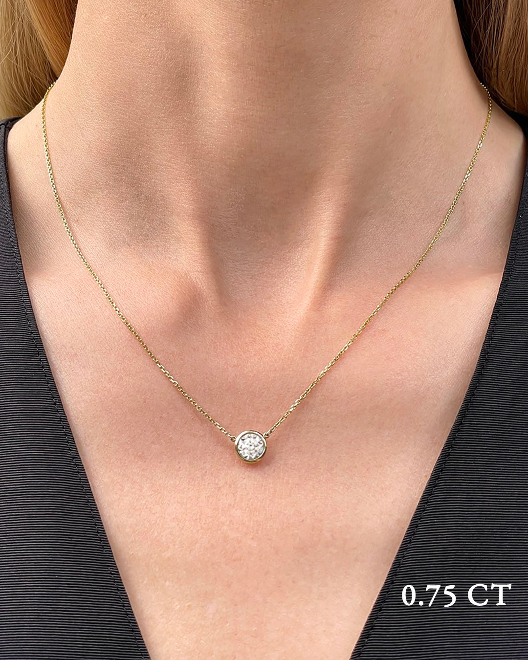 A delicate yellow gold necklace with a 0.75 carat diamond, bezel set, shown on a model's neck. 