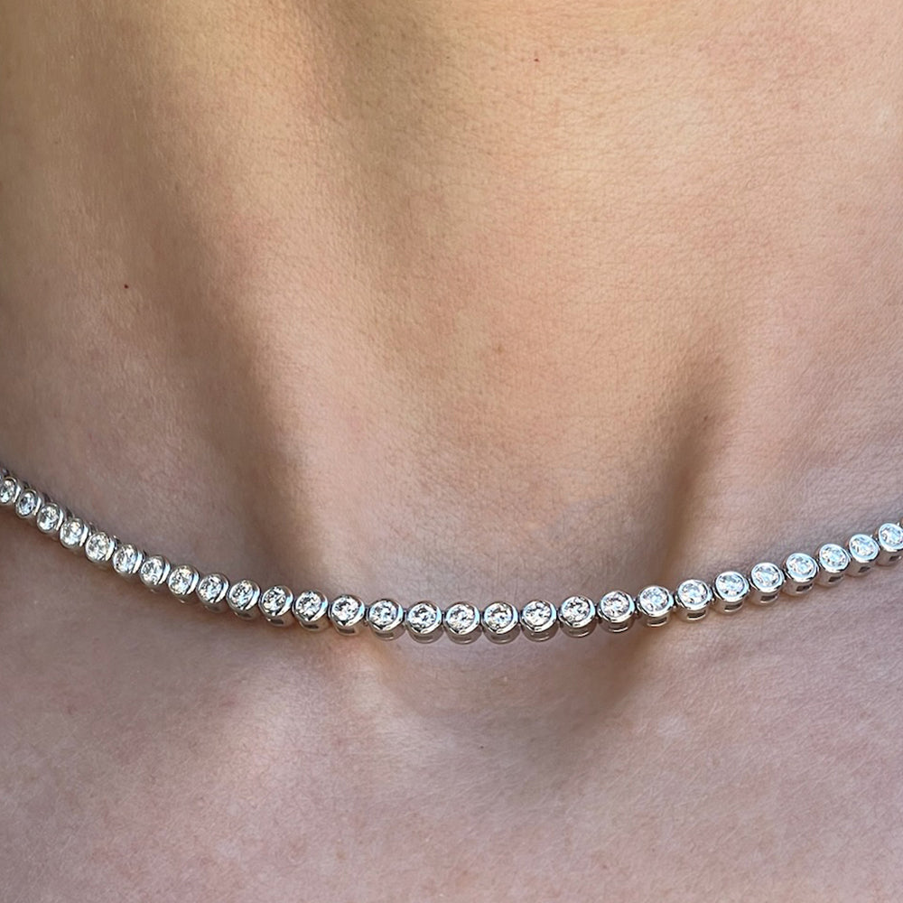 Bezel set diamond tennis necklace close-up on a model's neck.