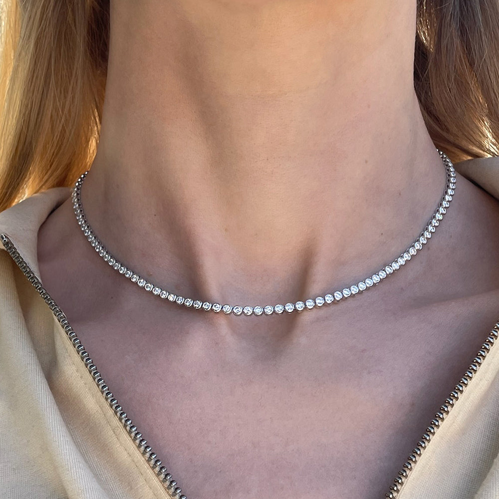A model wearing a 4.71 carat bezel set diamond tennis necklace in white gold.