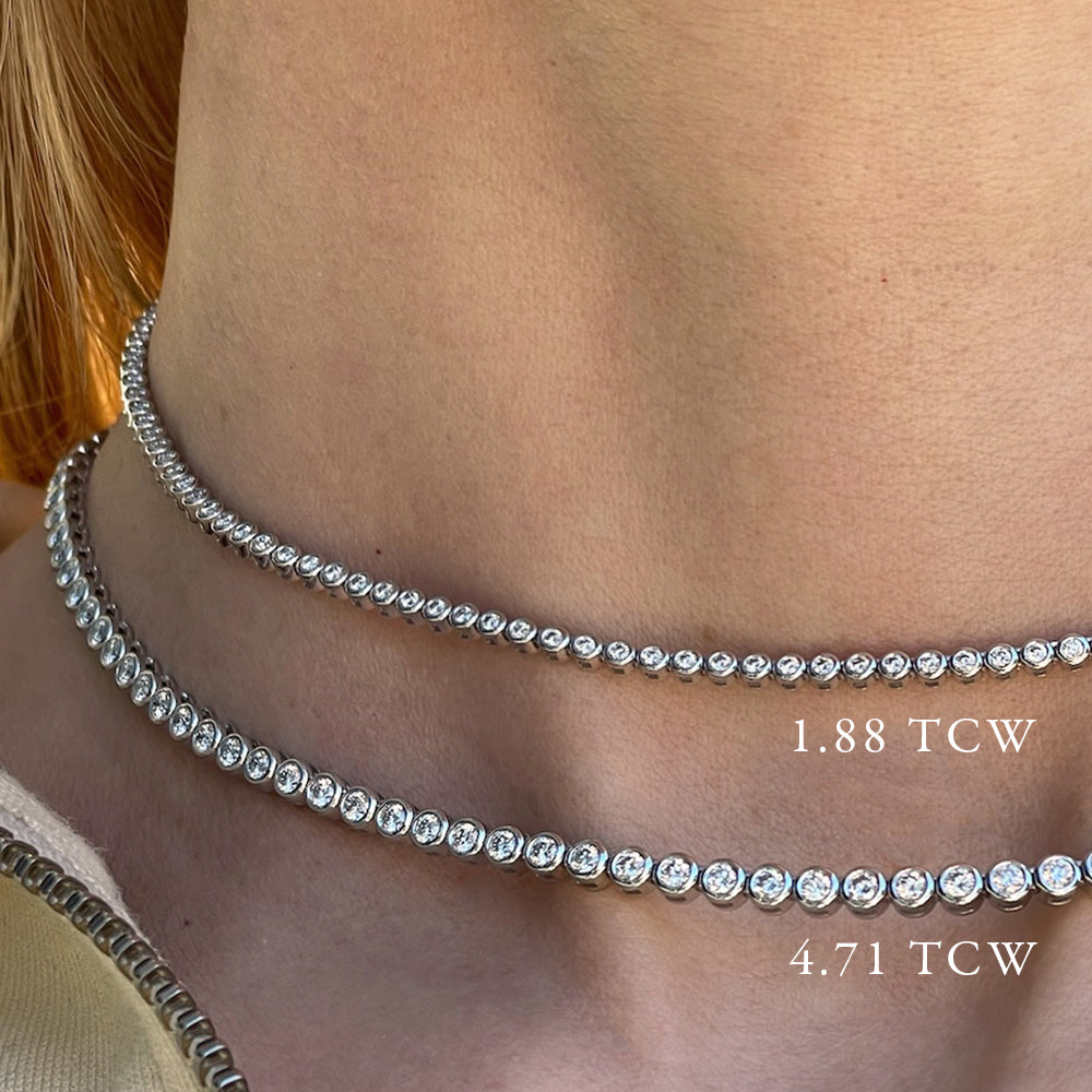 Two bezel set diamond tennis necklaces worn on a models neck, showing the size comparison between 4.71 carats and 1.88 carats.