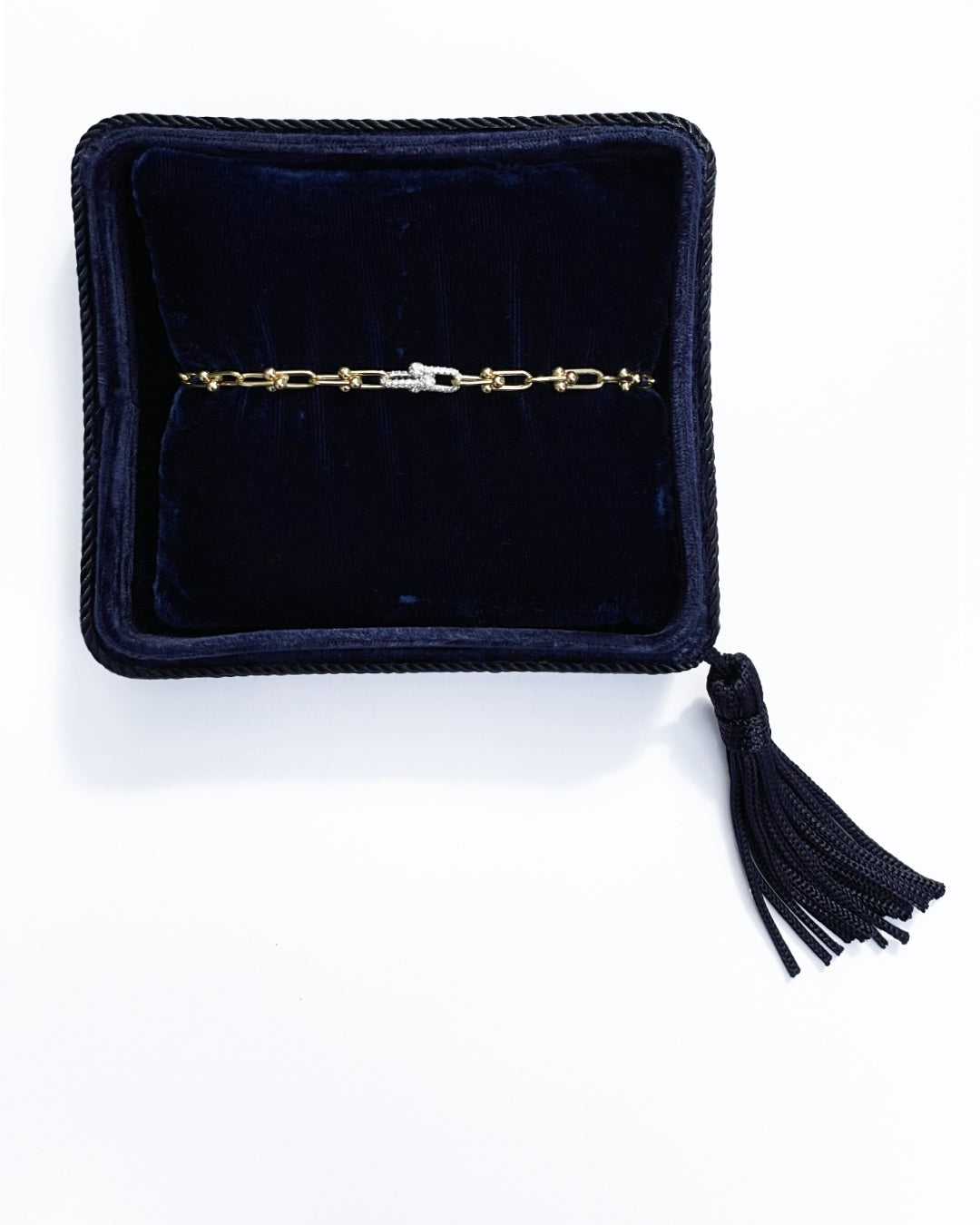 Diamond and Gold Ball Link Bracelet in 14K yellow gold, presented inside an open dark navy velvet jewelry box with a braided navy border and a tassel.