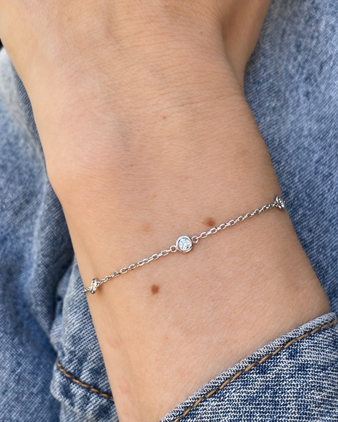 Bezel Set Diamond Station Bracelet in 14K white gold worn on a wrist, highlighting its delicate chain and diamond accents.