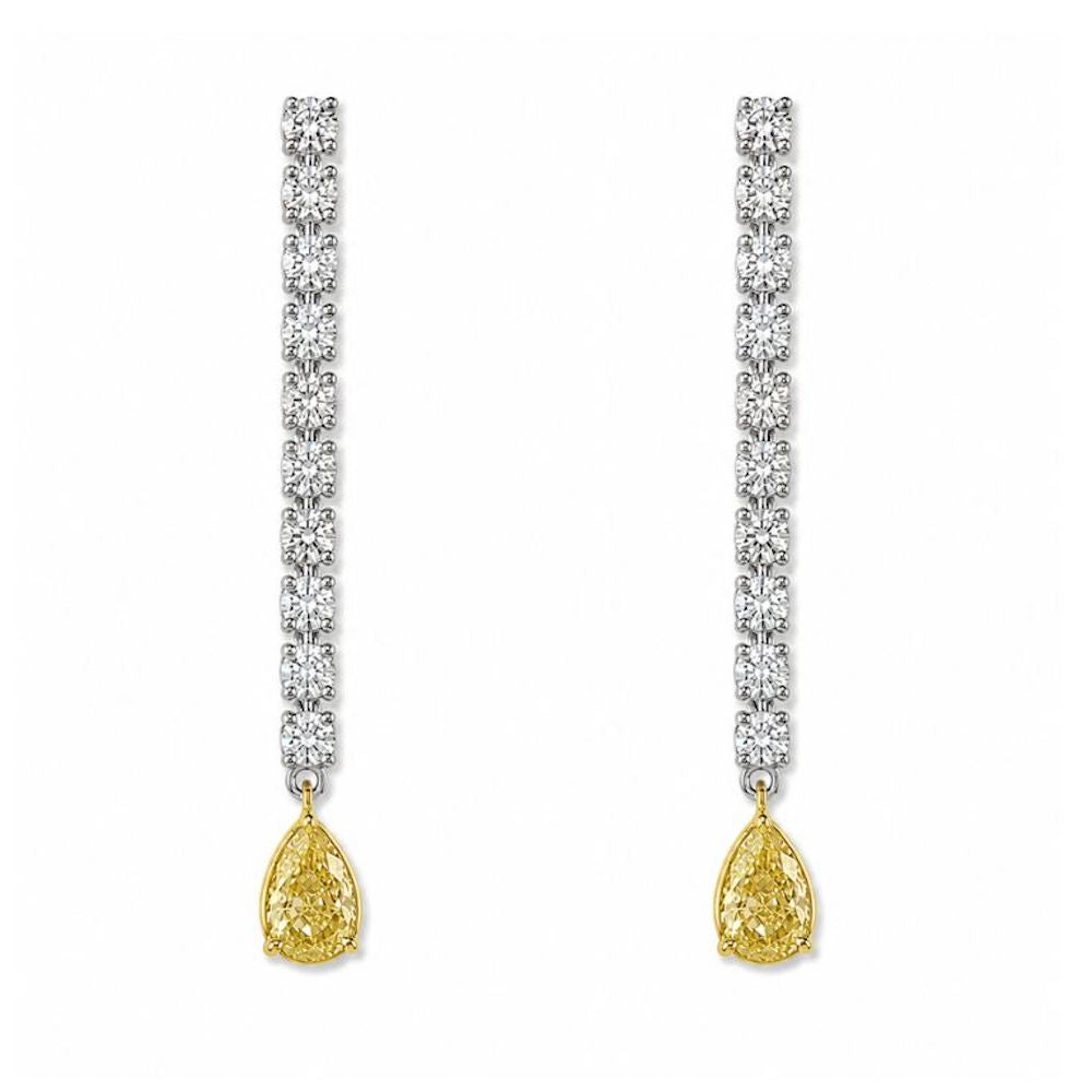 Pair of fancy yellow pear shape diamond drop earrings in 18K white gold featuring round brilliant cut white diamonds.