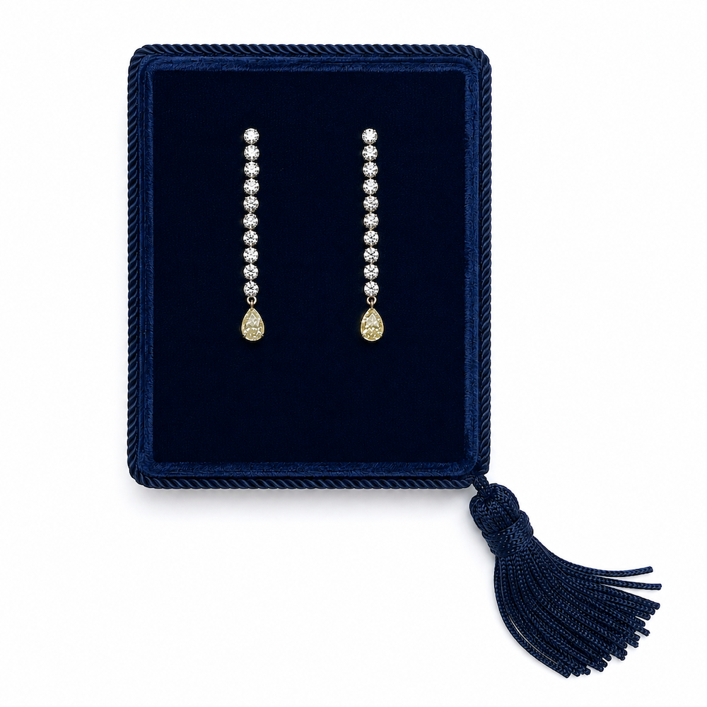 Pair of fancy yellow pear diamond drop earrings displayed in a luxury navy jewelry box