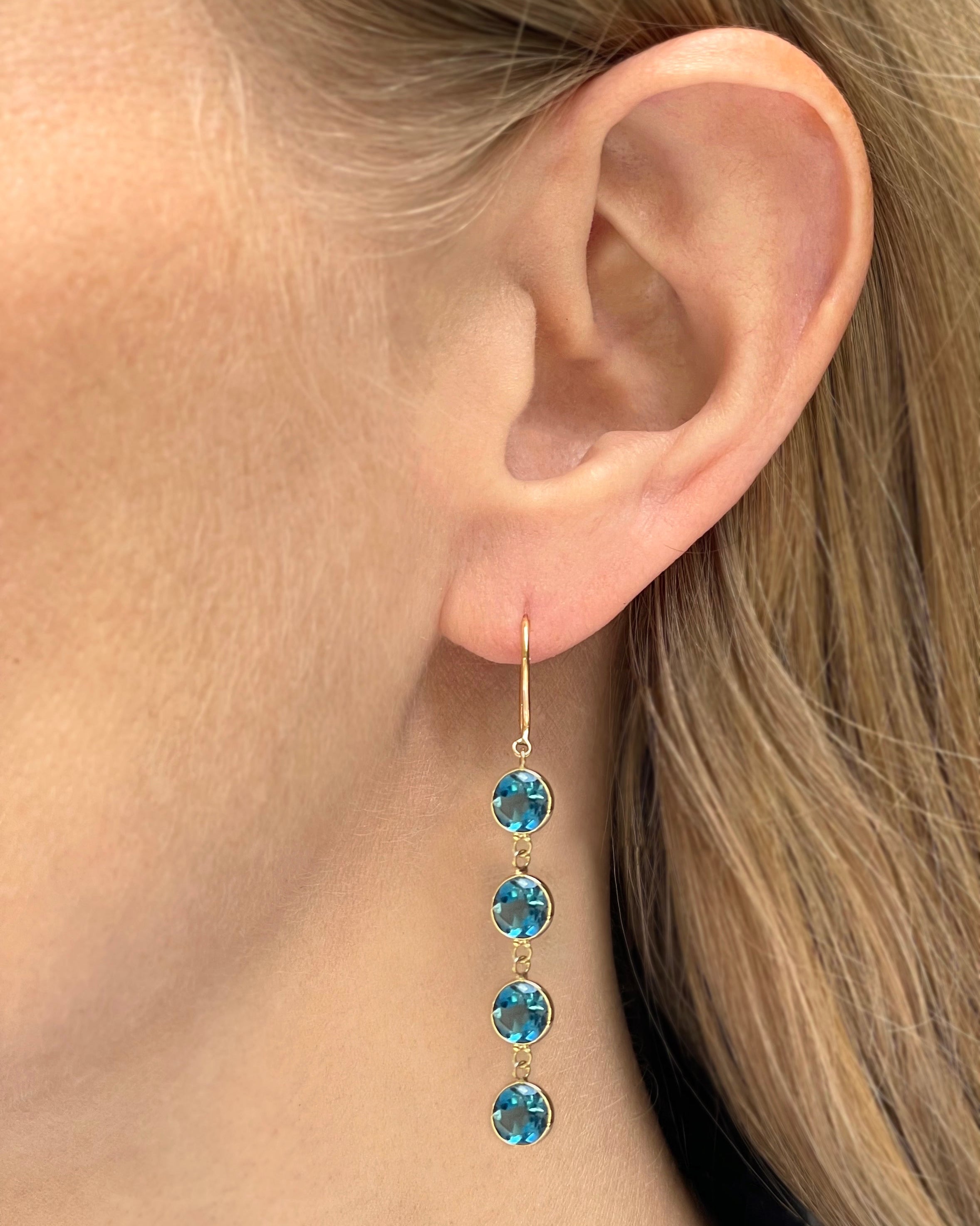 A model wearing yellow gold four stone London blue topaz drop earrings.