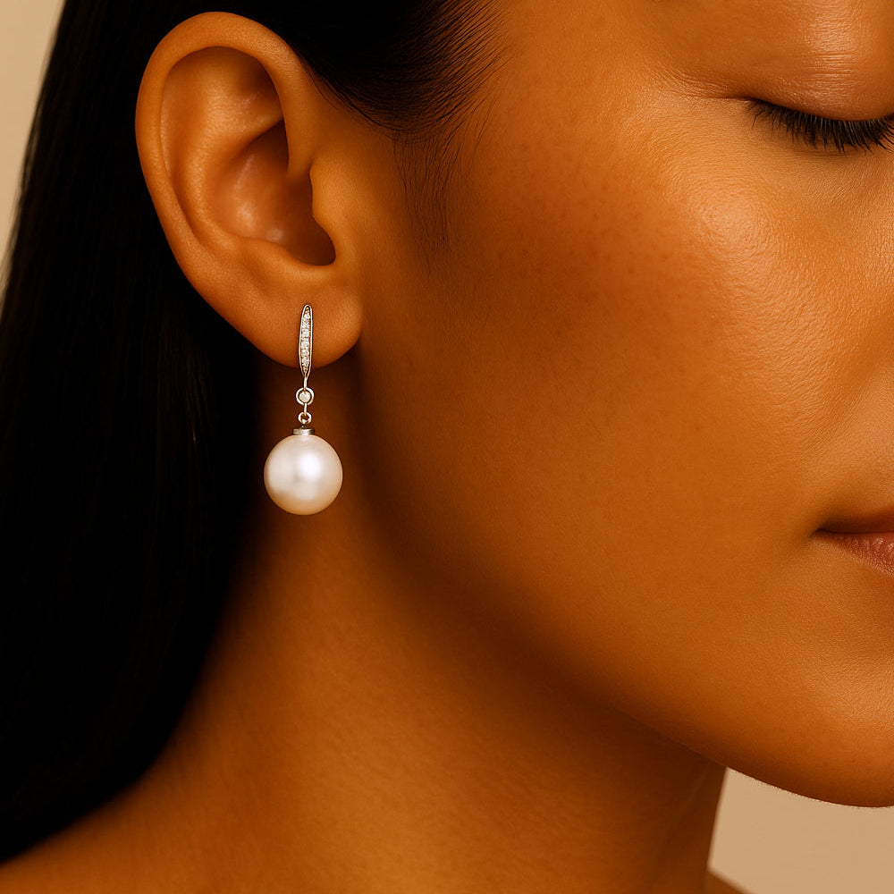 Close-up of a person wearing a pearl earring against a neutral background