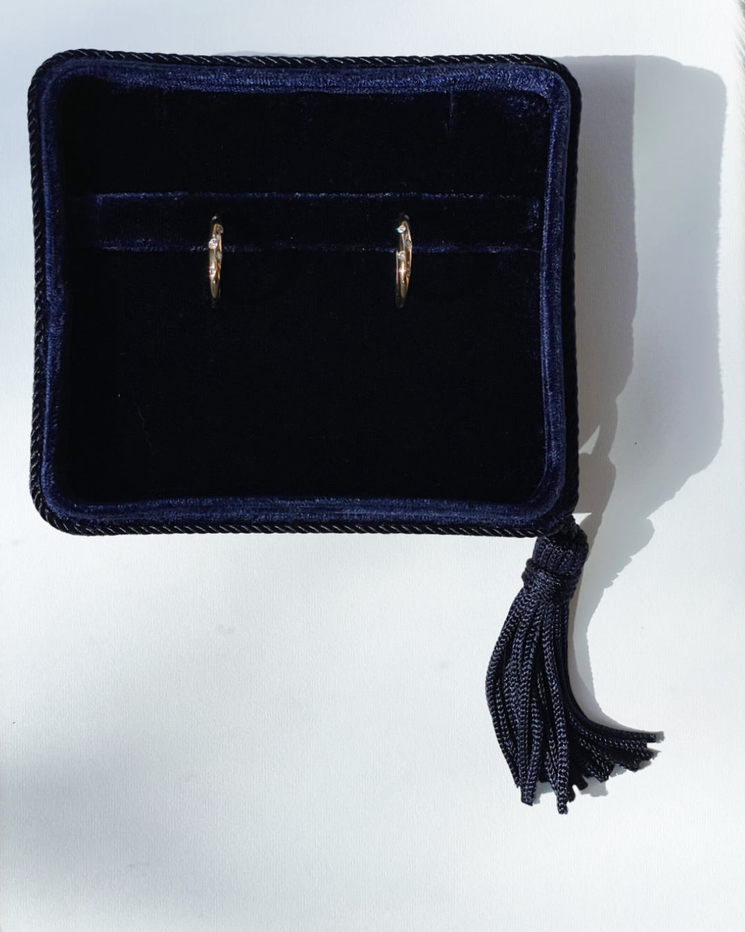Galaxy Diamond Hoop Earrings set in 14K rose gold displayed in a navy velvet Marisa Perry jewelry box, featuring scattered round brilliant-cut diamonds in a burnished setting.