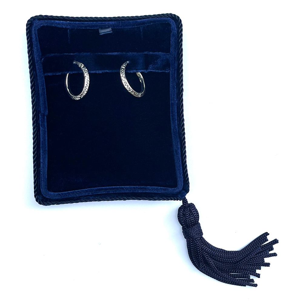 White gold oval hoop earrings displayed in a luxury navy jewelry box.