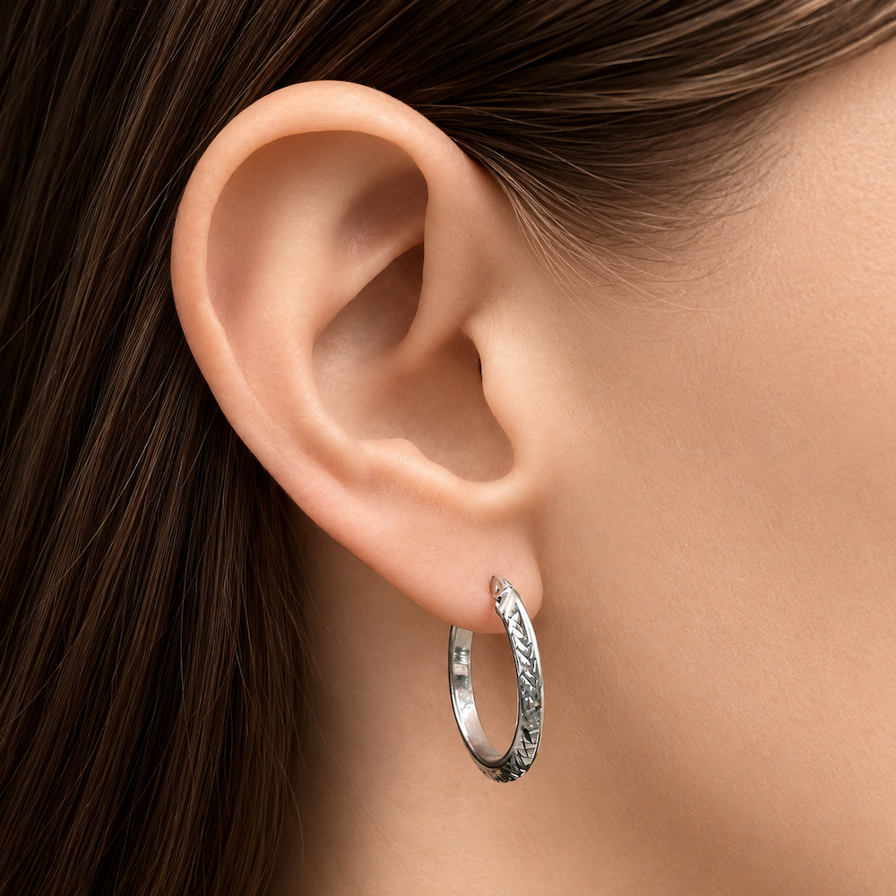 White gold hoop earring worn by a model with brown hair.