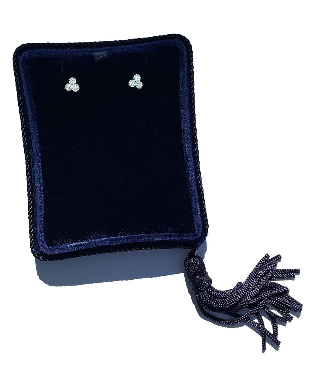 A pair of large 14k white gold stud earrings featuring 3 round brilliant-cut diamond clusters per earring, displayed in a dark navy velvet jewelry pouch with a braided tassel, set against a plain white background.
