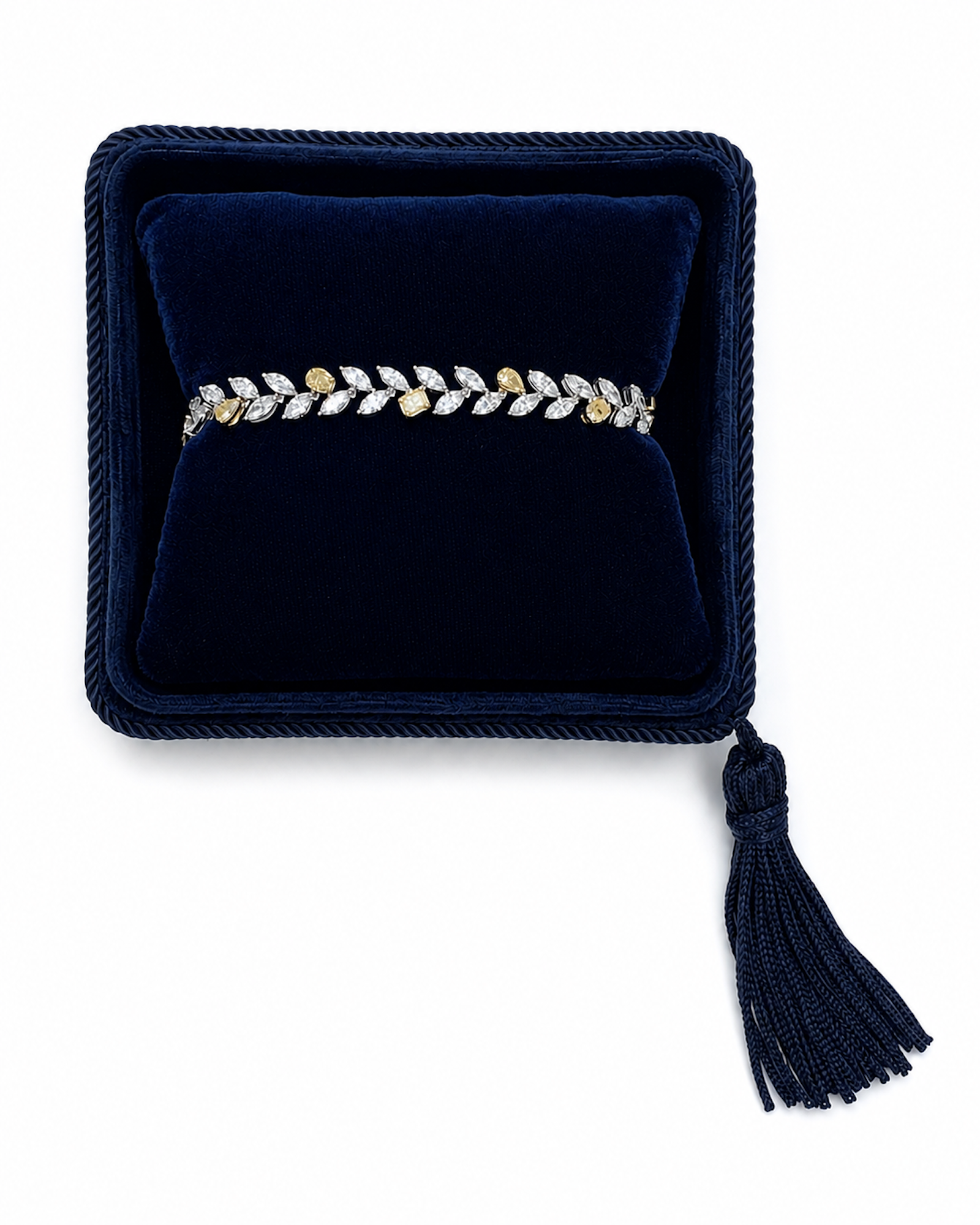A delicate leaf-patterned mixed shape white and yellow diamond bracelet, displayed in a dark navy velvet Marisa Perry jewelry box with a tassel.