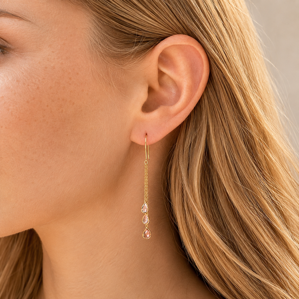 Close-up of a model’s ear wearing yellow gold multi-color sapphire chain drop earrings.