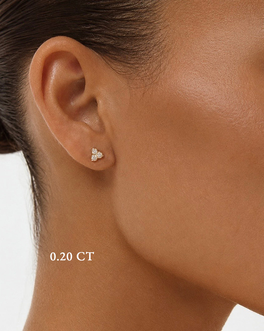 Close-up of a model wearing petite trilogy diamond earrings in rose gold.