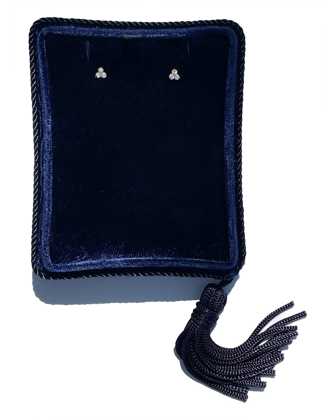 Petite trilogy diamond stud earrings displayed in a luxury navy jewelry box.