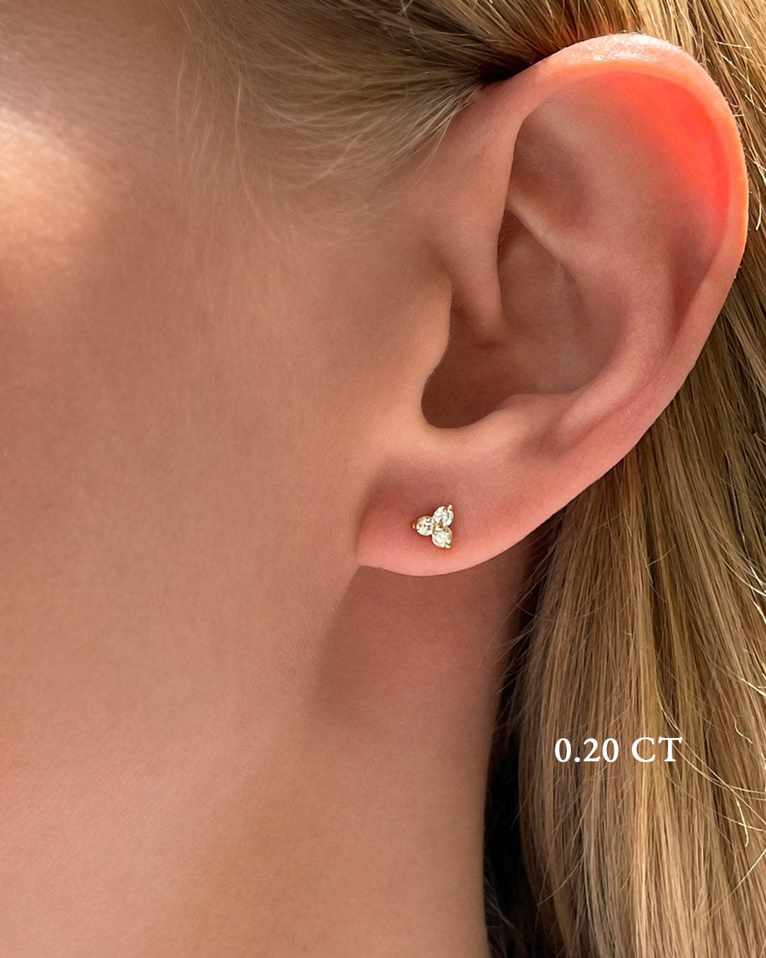 Close-up of a model wearing petite trilogy diamond earring in yellow gold.