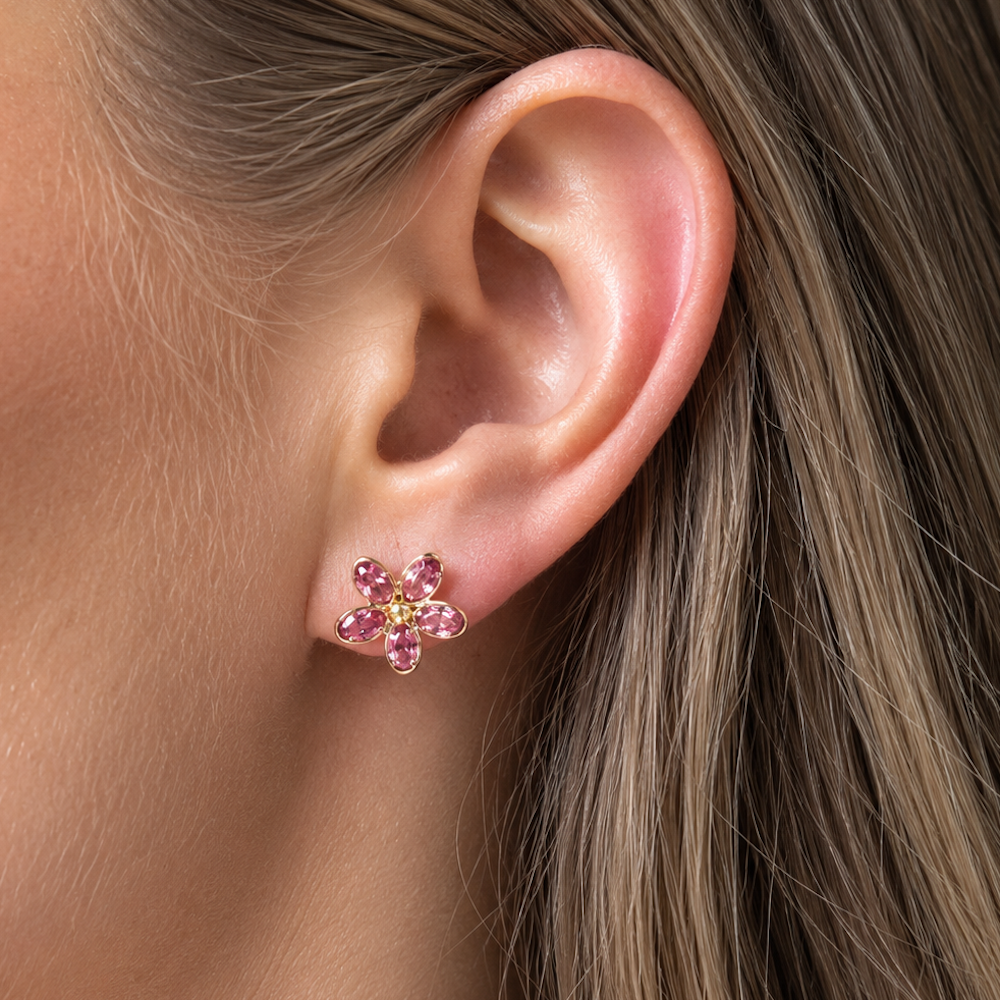 Close-up of a model’s ear wearing a pink sapphire flower-shaped stud earring.
