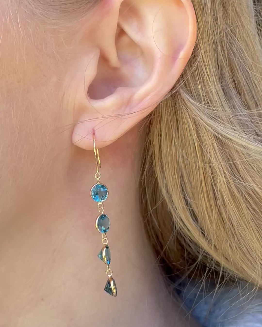 A model slowly moving, showing different angles of four stone london blue topaz drop earrings.