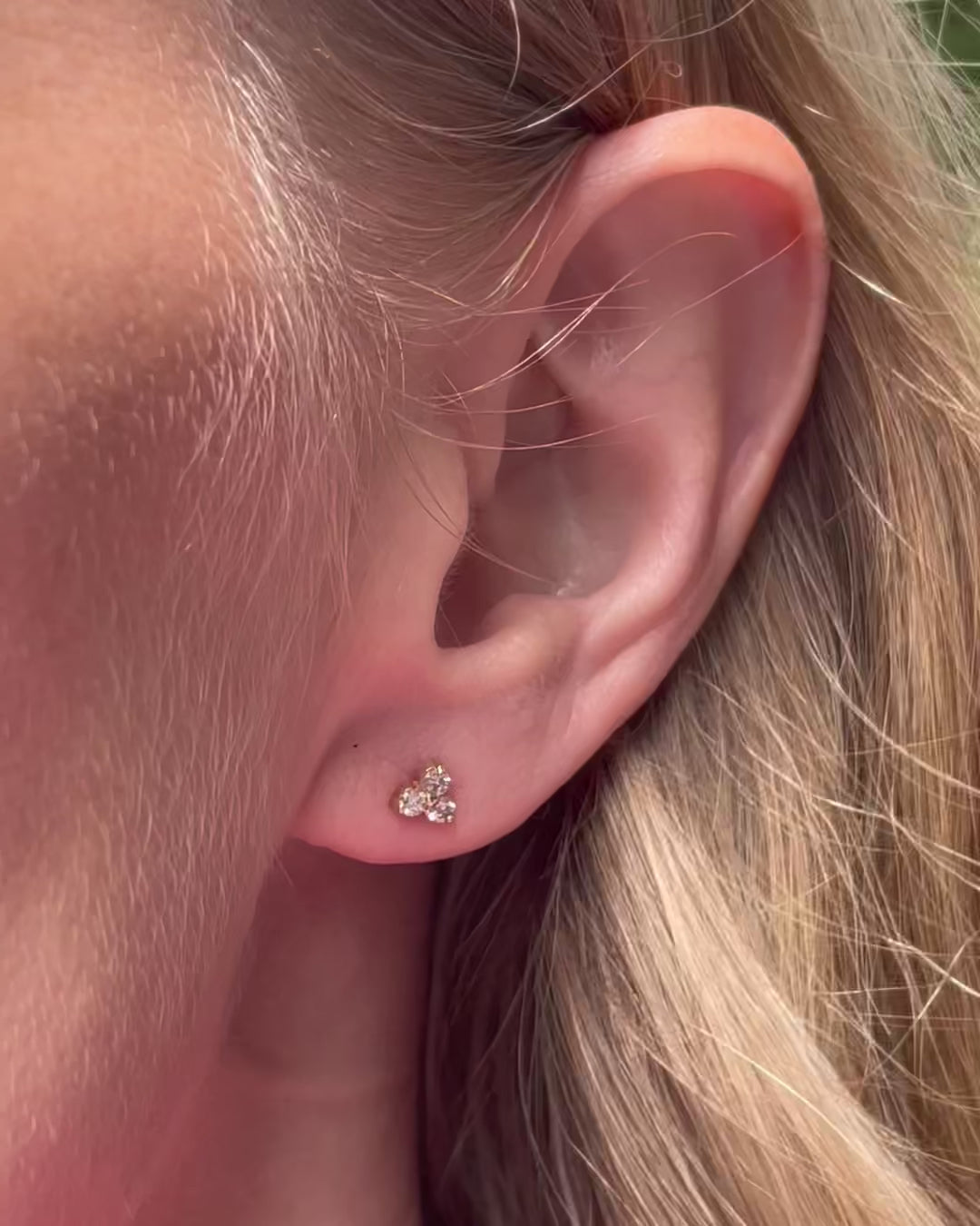 A model slowly moving, showing different angles of extra small diamond trilogy stud earring.