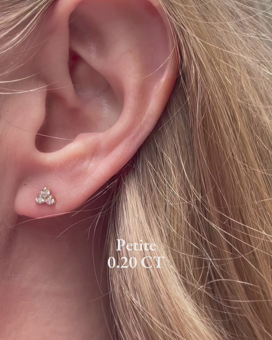 A model moving slowly, showing diamond trilogy stud earrings in a variety of carat weights from 0.20 carats up to 1 carat.