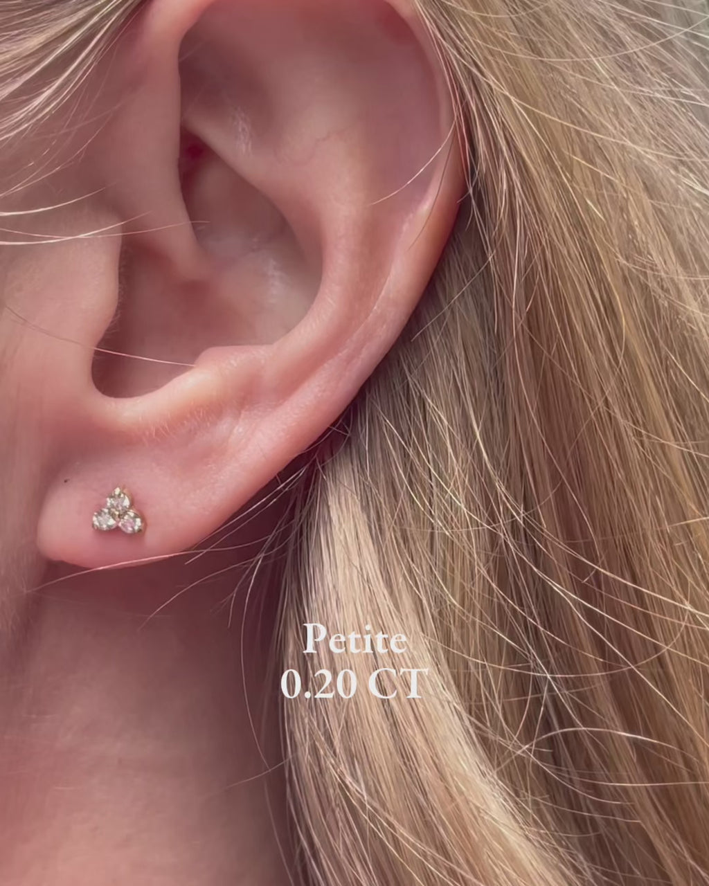 A model moving slowly, showing diamond trilogy stud earrings in a variety of carat weights from 0.20 carats up to 1 carat.
