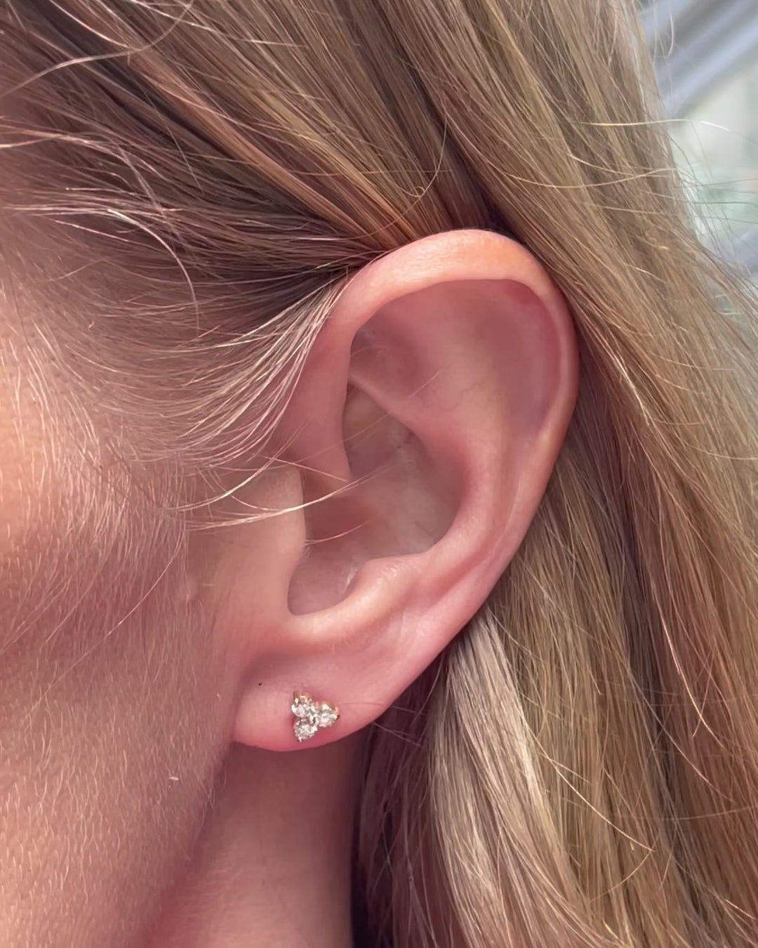 A model moving slowly, showing different angles of the small diamond trilogy stud earring in yellow gold.