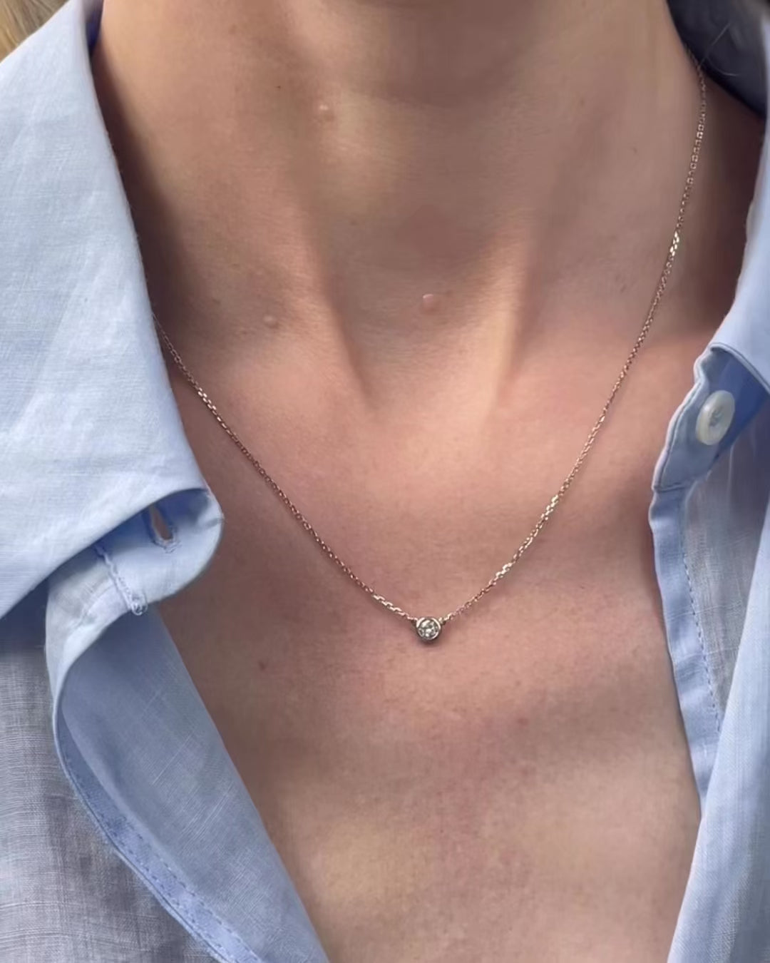 A model moving slowly, from far to close-up, showing details of the 0.15 ct bezel set diamond pendant necklace in 14k white gold.