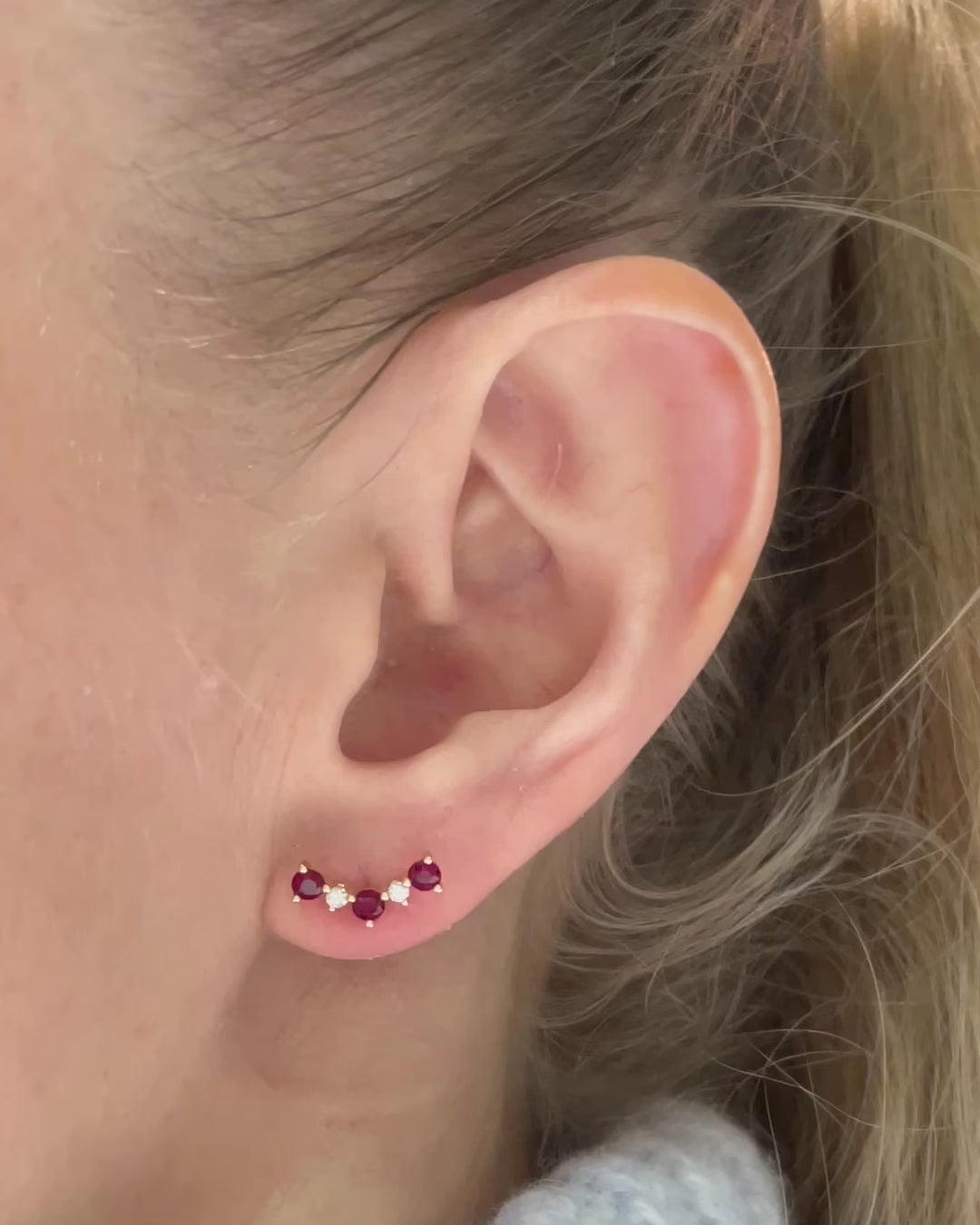 Model moving slowly wearing ruby and diamond cluster stud earrings.
