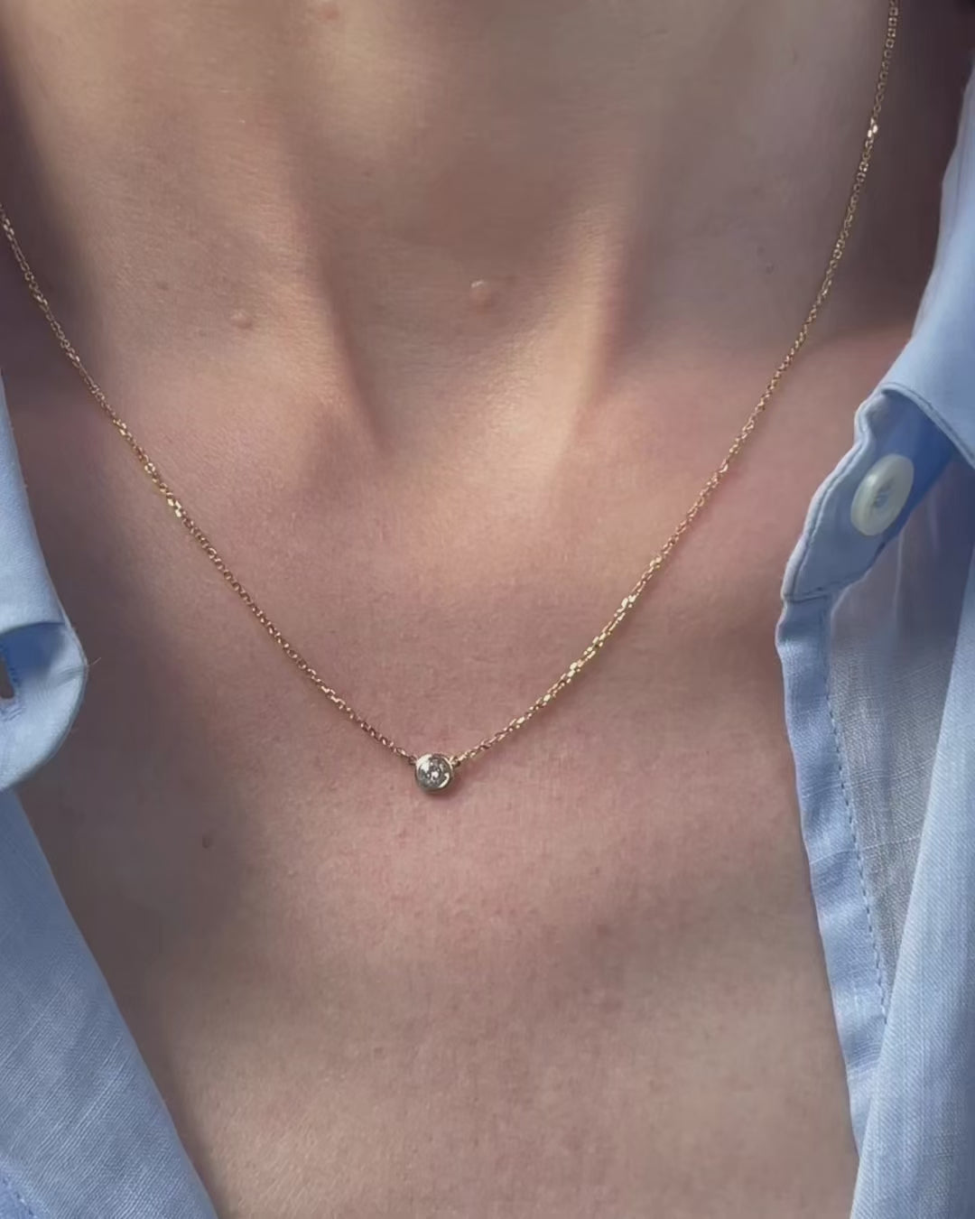A model moving slowly, from far to close-up, showing details of the 0.15 ct bezel set diamond pendant necklace in 14k yellow gold.