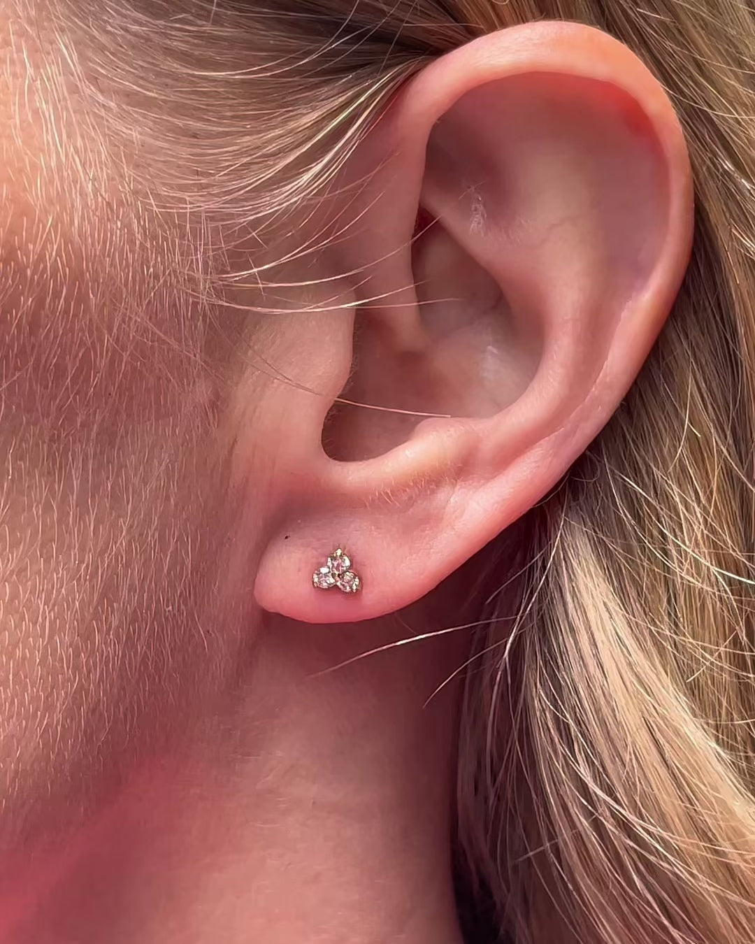 Video showcasing petite trilogy diamond stud earrings in 14K yellow gold worn by a model.