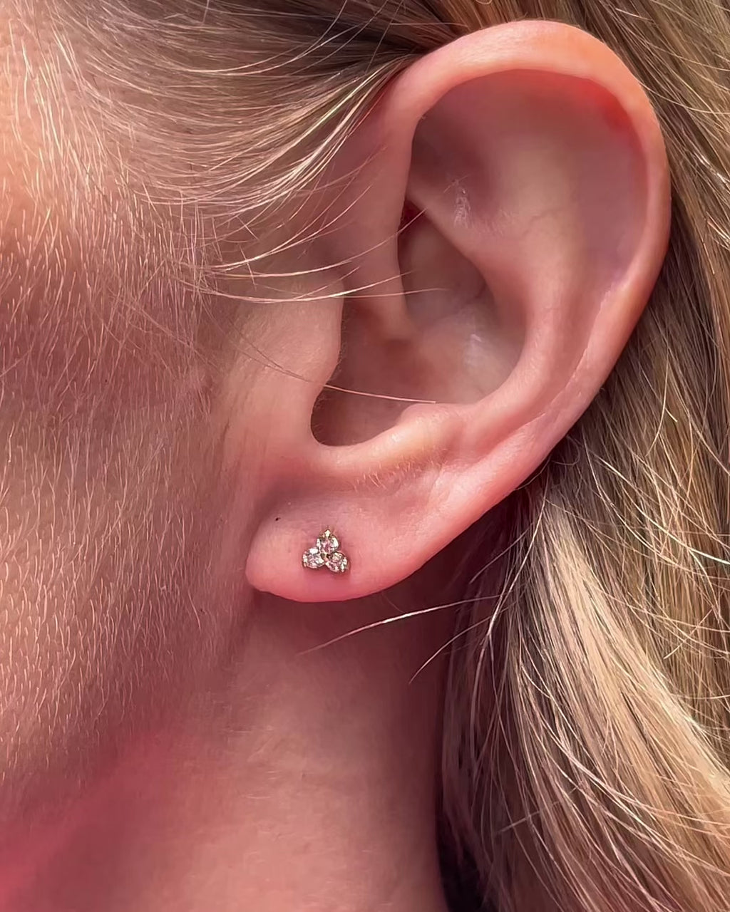 Video showcasing petite trilogy diamond stud earrings in 14K yellow gold worn by a model.