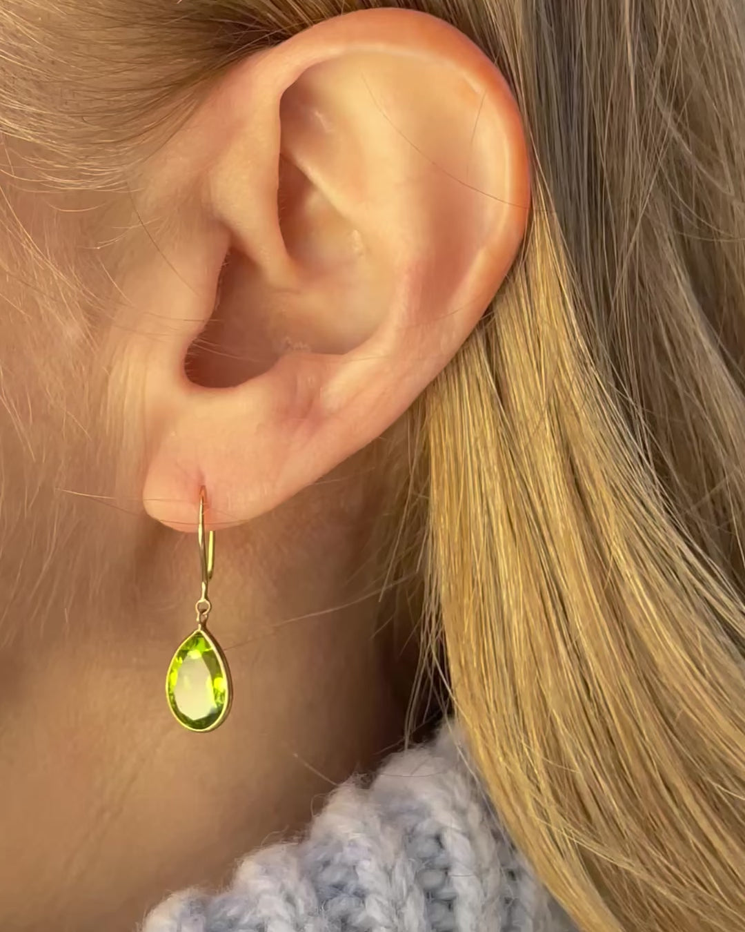 A model slowly moving, showing different angles of pear shape peridot drop earrings.