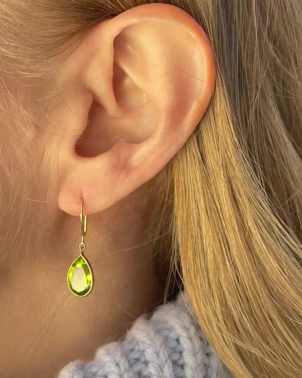 A model slowly moving, showing different angles of pear shape peridot drop earrings.