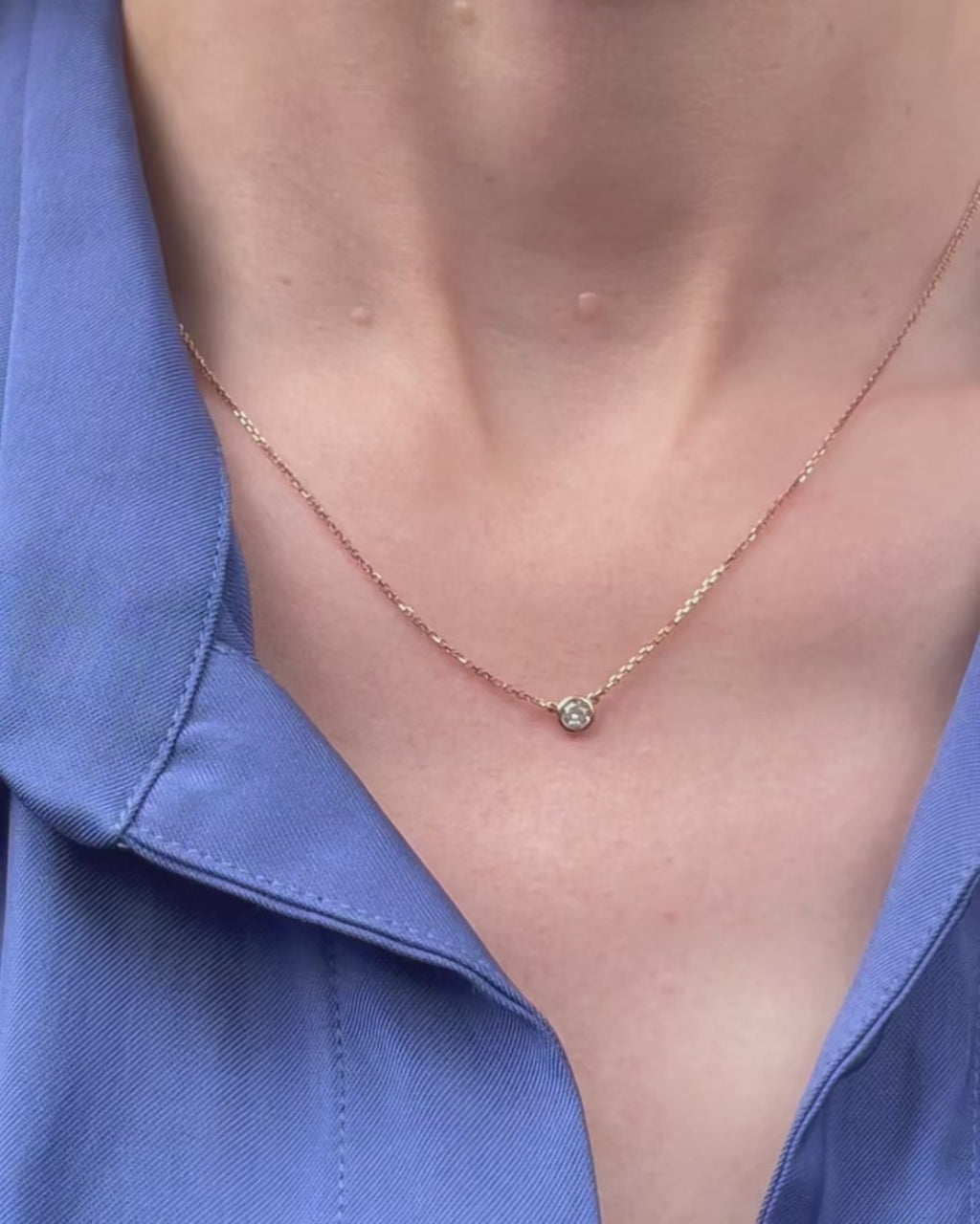 A model moving slowly, from far to close-up, showing details of the 0.15 ct bezel set diamond pendant necklace in 14k rose gold.
