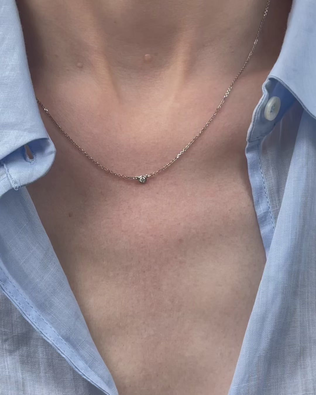 A model moving slowly, from far to close-up, showing details of the 0.05 ct bezel set diamond pendant necklace in 14k white gold.