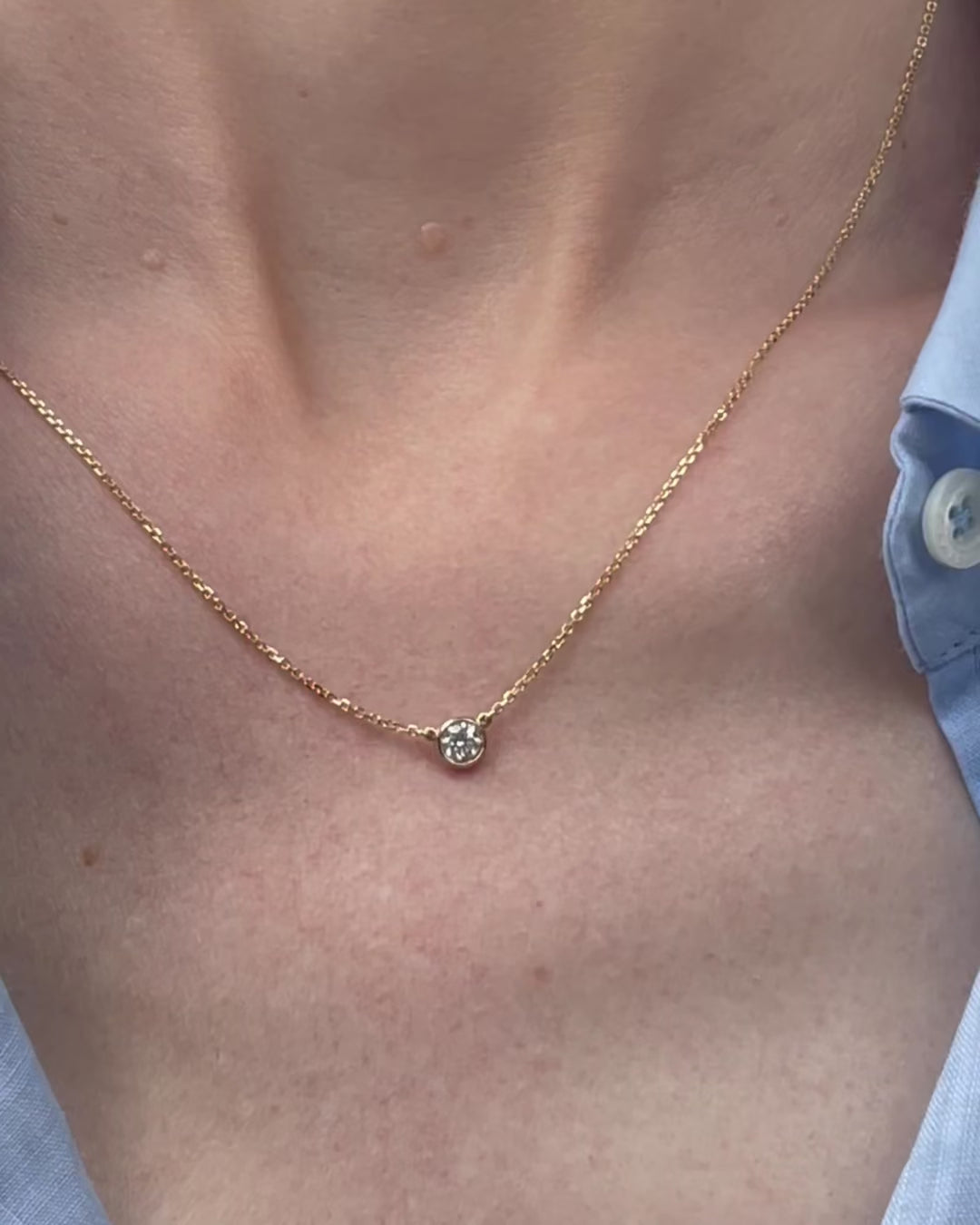 A model moving slowly, from far to close-up, showing details of the 0.25 ct bezel set diamond pendant necklace in 14k yellow gold.